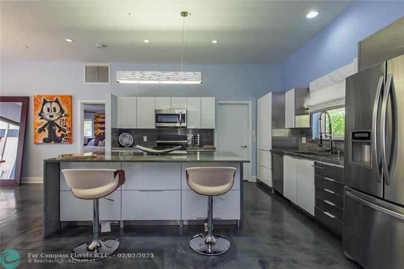 930 Northwest 4th Court Boca Raton, FL 33432 - Photo 7 of 28 a kitchen with stainless steel appliances granite countertop a refrigerator a sink a stove a dining table and chairs