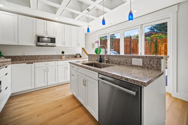 a kitchen with granite countertop stainless steel appliances sink stove microwave and cabinets