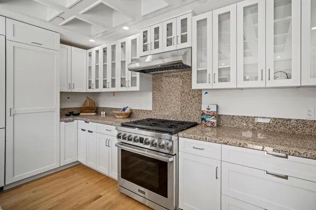 a kitchen with stainless steel appliances granite countertop a stove and a white cabinets