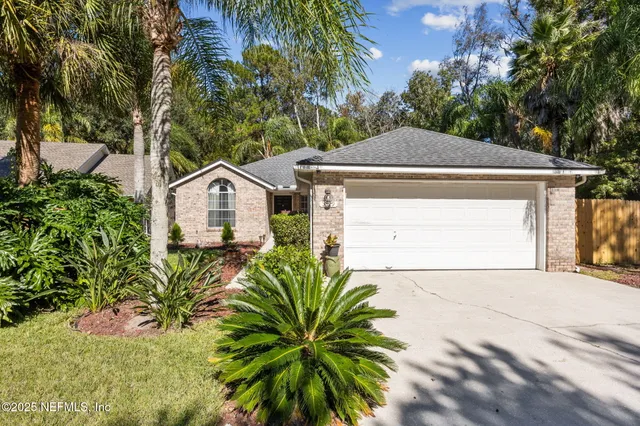 a front view of a house with a garden and trees
