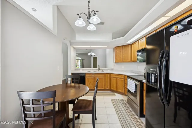 a kitchen with stainless steel appliances granite countertop a sink a stove top oven a dining table and chairs with wooden floor