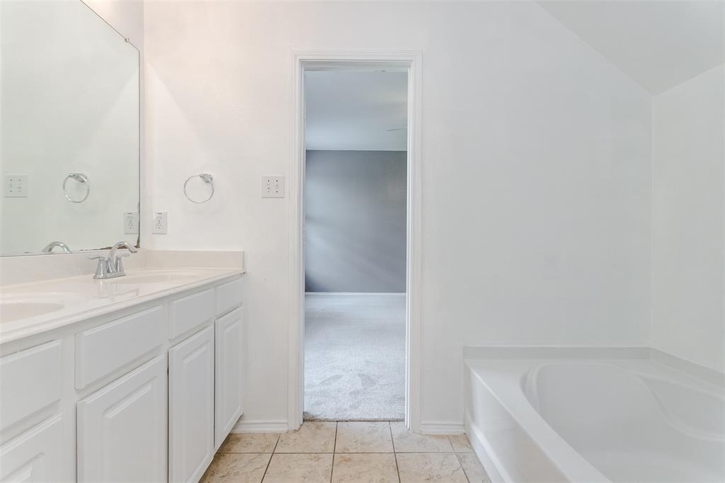 203 Arabian Road Waxahachie, TX 75165 - Photo 14 of 24 Bathroom featuring a dual-sink vanity with white cabinetry, a built-in bathtub, and tile flooring