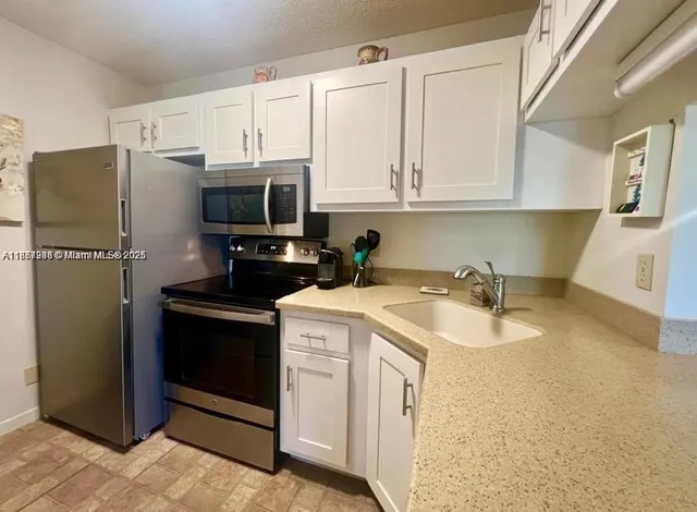 a kitchen with stainless steel appliances granite countertop a refrigerator a stove a sink and dishwasher