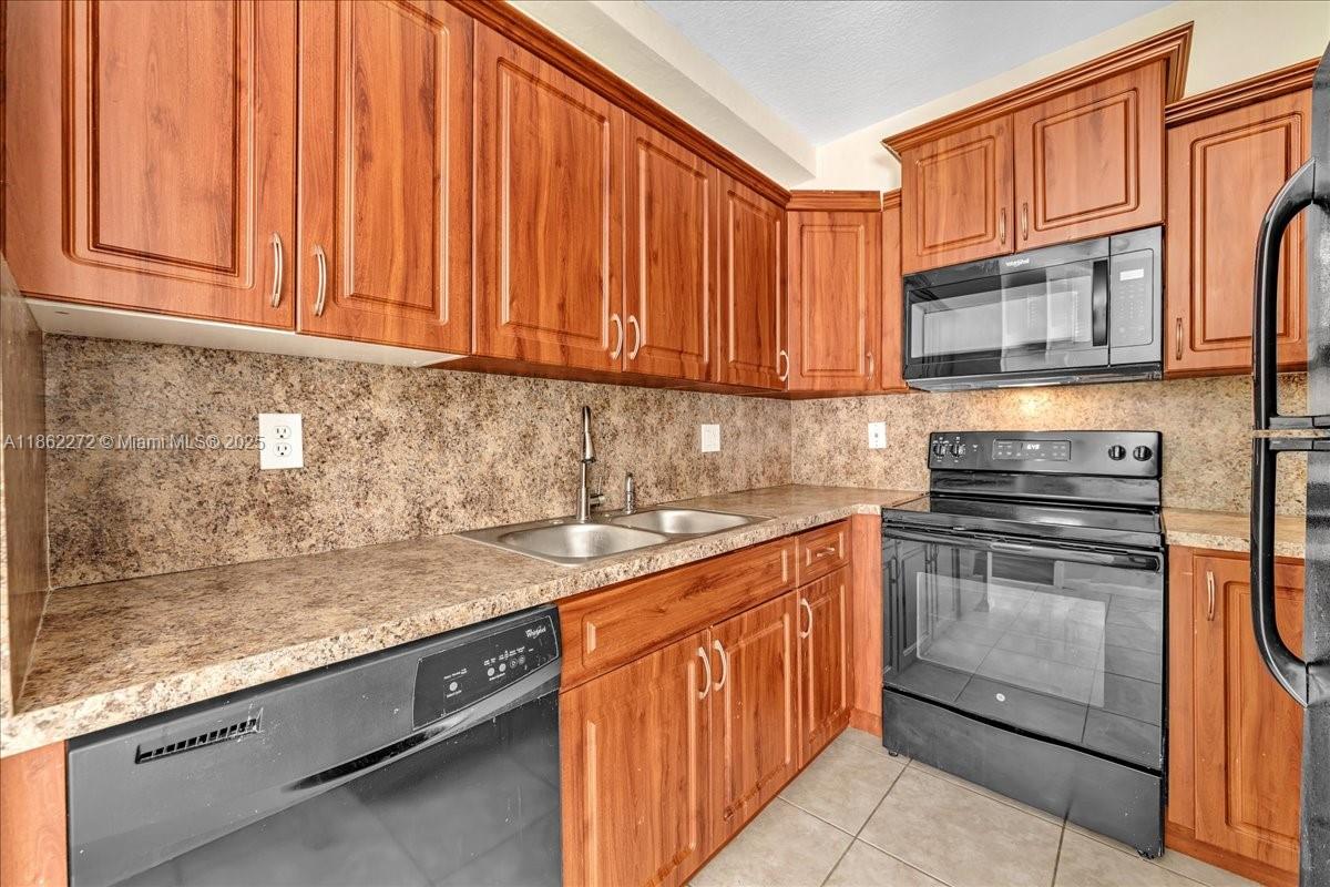 12252 Southwest 25th Court, Unit 1614 Miramar, FL 33025 - Photo 16 of 46 a kitchen with stainless steel appliances granite countertop a sink stove and cabinets