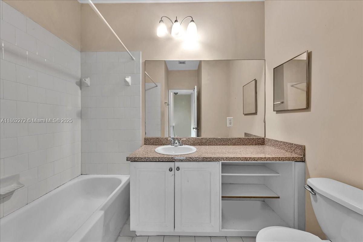 12252 Southwest 25th Court, Unit 1614 Miramar, FL 33025 - Photo 30 of 46 a bathroom with a granite countertop sink a toilet a mirror and bathtub