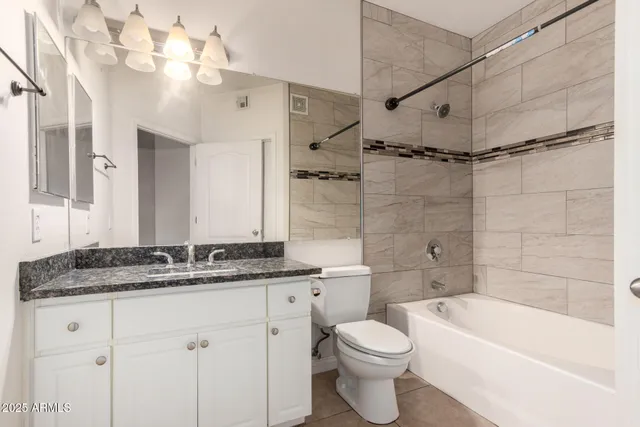 a bathroom with a granite countertop sink a toilet and bathtub