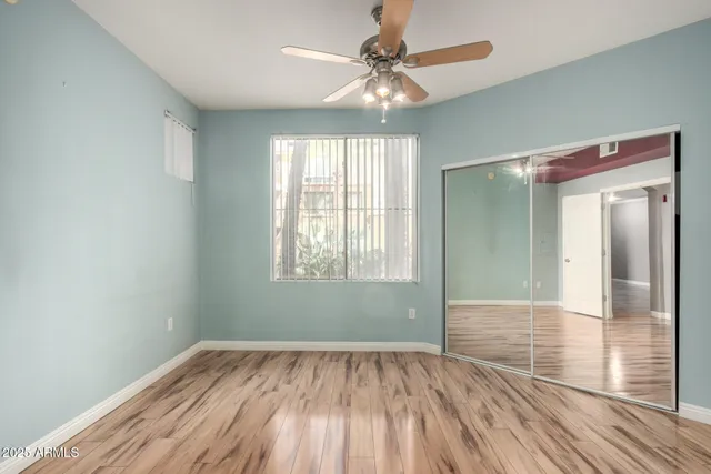 an empty room with wooden floor fan and windows