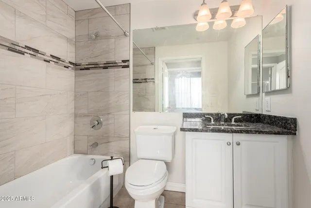 a bathroom with a granite countertop sink mirror toilet and bathtub