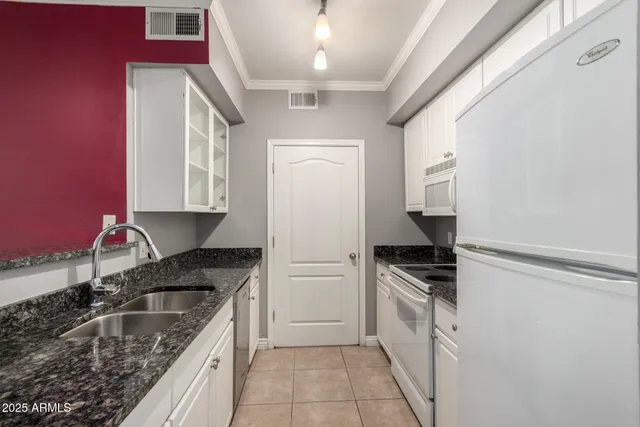 a kitchen with granite countertop a sink stove and refrigerator