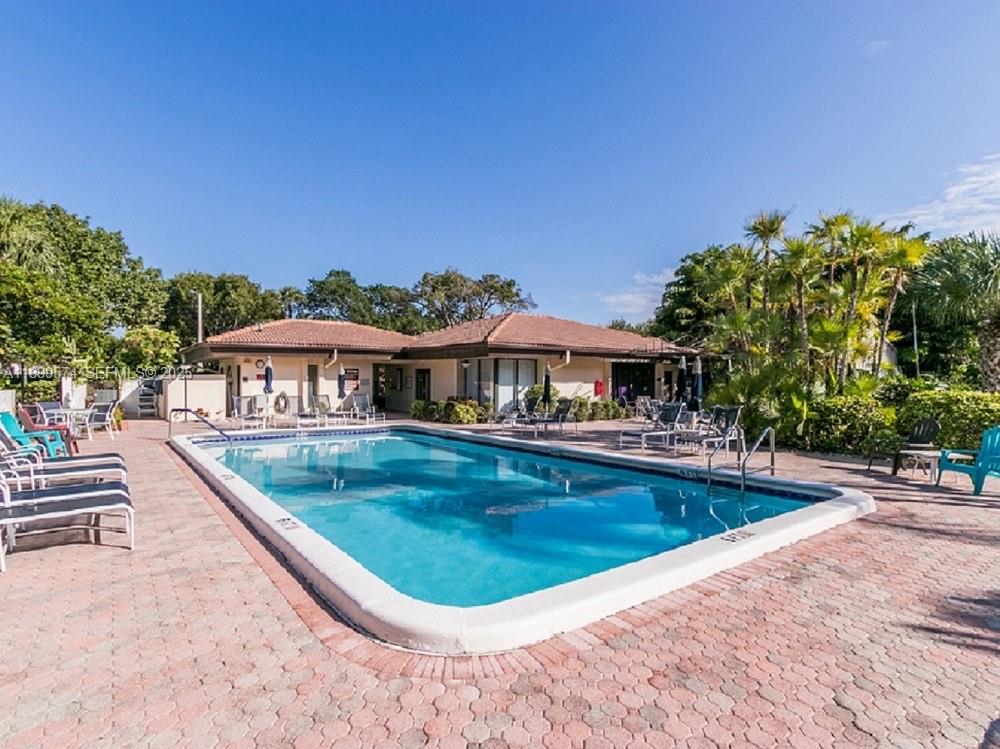 21643 Cypress Road, Unit 14D Boca Raton, FL 33433 - Photo 25 of 26 a view of a swimming pool with lawn chairs under an umbrella