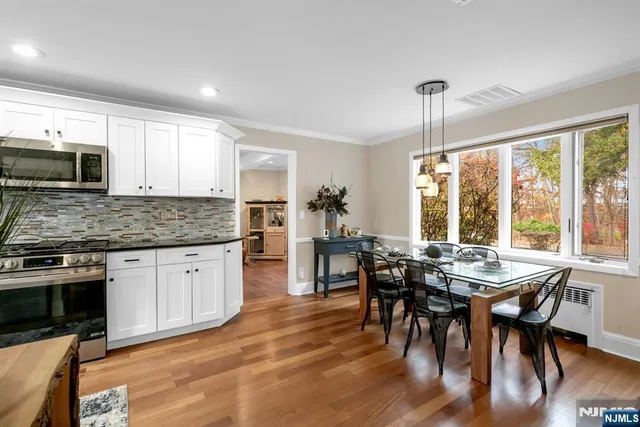 a kitchen with stainless steel appliances granite countertop wooden floor dining table and chairs