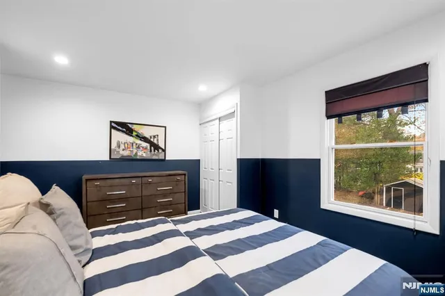 a bedroom with a bed and a dresser with wooden floor