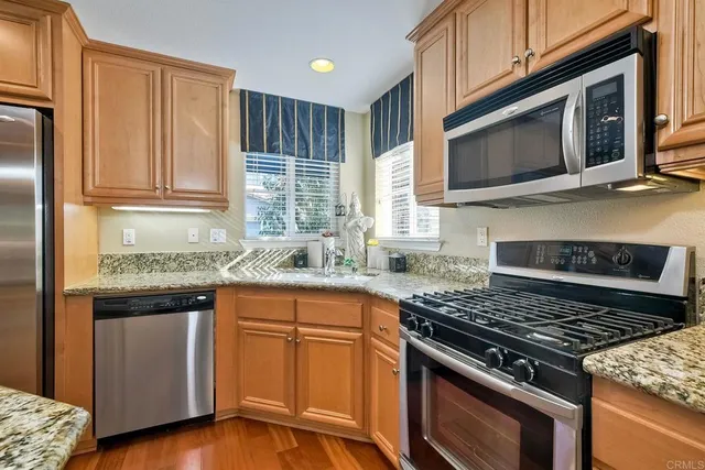 a living room with stainless steel appliances furniture a rug and a kitchen view