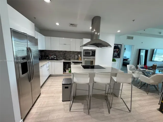 a kitchen with stainless steel appliances kitchen island granite countertop a refrigerator and a stove top oven