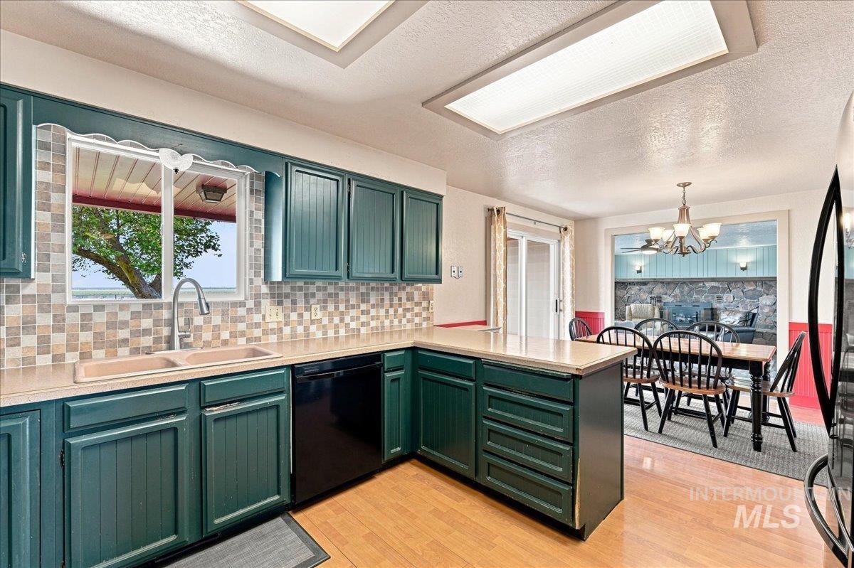 26201 Hop Road Caldwell, ID 83607 - Photo 10 of 45 Kitchen with teal cabinetry, tile backsplash, laminate countertops, and wood-finish flooring