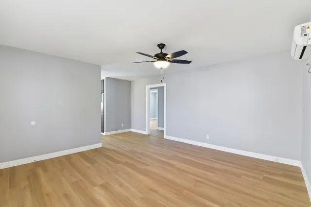 a view of an empty room with chandelier fan and wooden floor