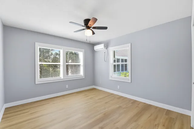 a view of an empty room with a window and wooden floor