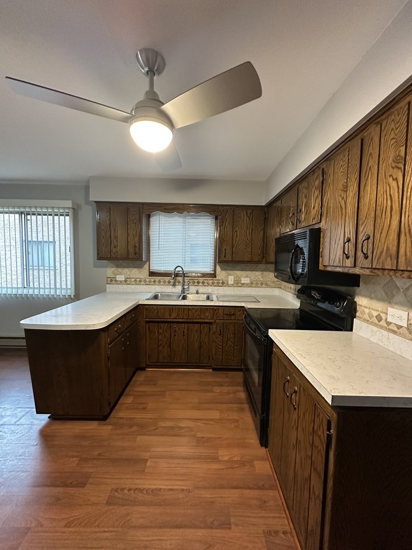 6334 West 65th Street, Unit 2N Chicago, IL 60638 - Photo 5 of 9 a large kitchen with stainless steel appliances kitchen island granite countertop a stove a sink dishwasher and a refrigerator with wooden cabinets