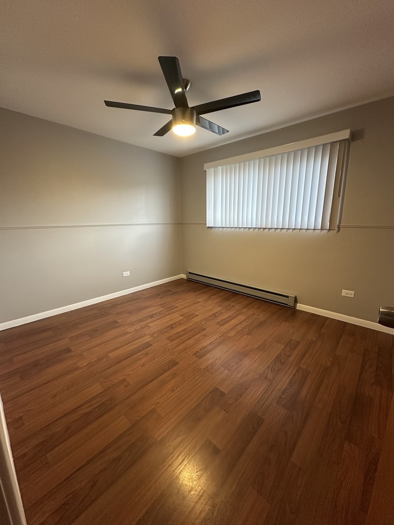 6334 West 65th Street, Unit 2N Chicago, IL 60638 - Photo 7 of 9 an empty room with wooden floor fan and windows