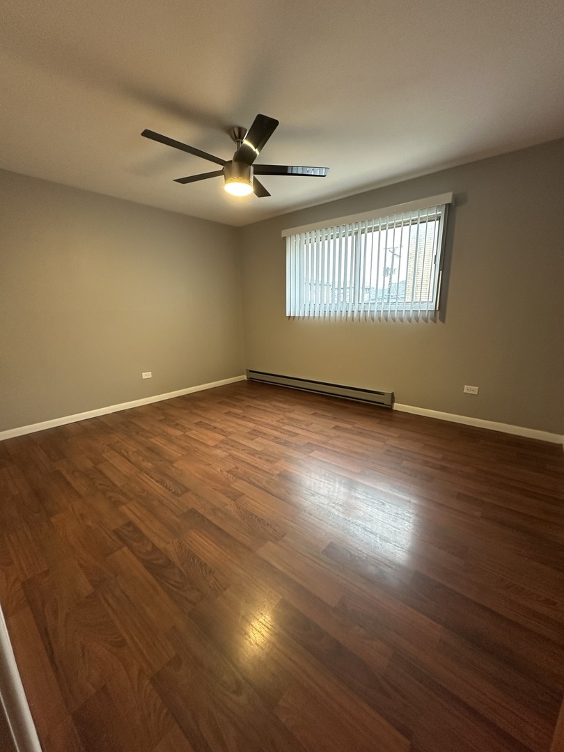 6334 West 65th Street, Unit 2N Chicago, IL 60638 - Photo 8 of 9 an empty room with wooden floor fan and windows