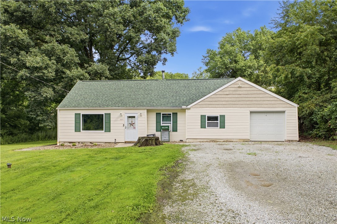 1057 Center Road Clinton, OH 44216 - Photo 1 of 24 Exterior featuring horizontal siding, green shingle roofing, attached garage, and a gravel driveway