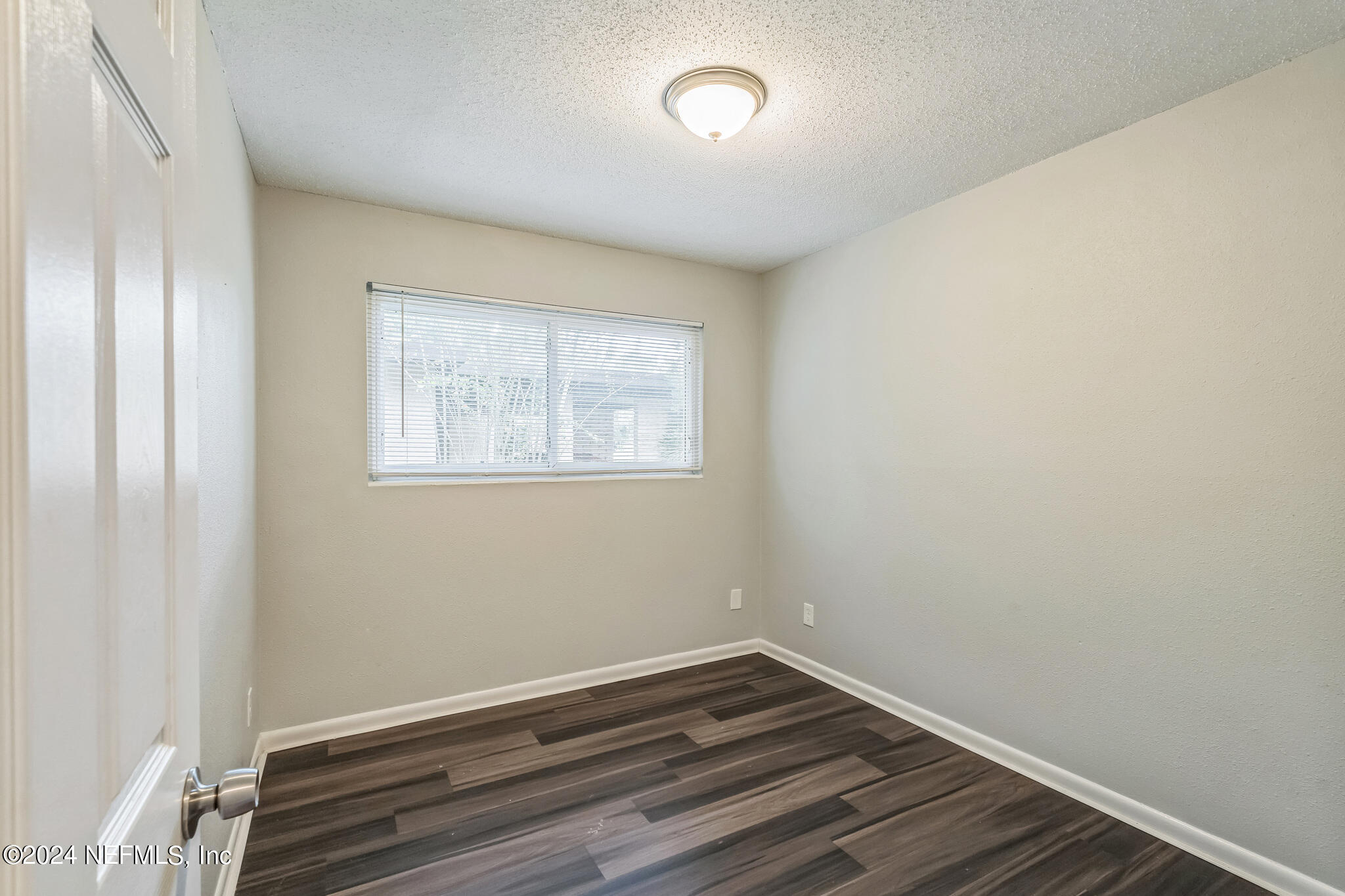 6974 Rollo Road Jacksonville, FL 32205 - Photo 11 of 16 a view of an empty room with wooden floor and a window