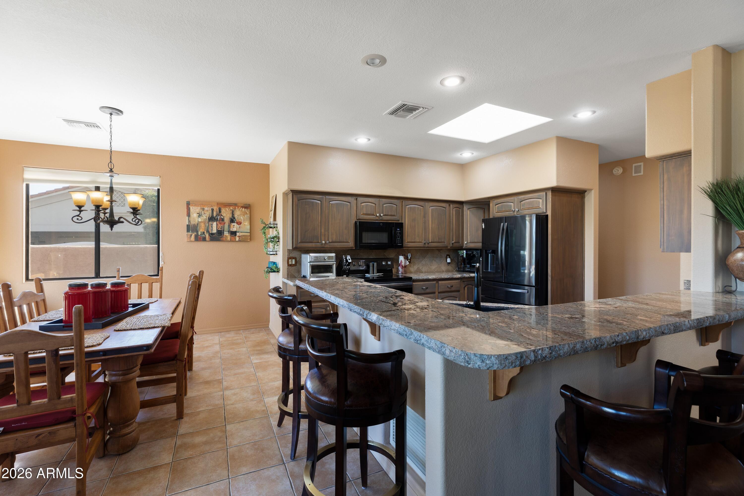 18622 North Tonto Verde Drive Rio Verde, AZ 85263 - Photo 3 of 47 a kitchen with stainless steel appliances kitchen island granite countertop a table chairs stove and refrigerator