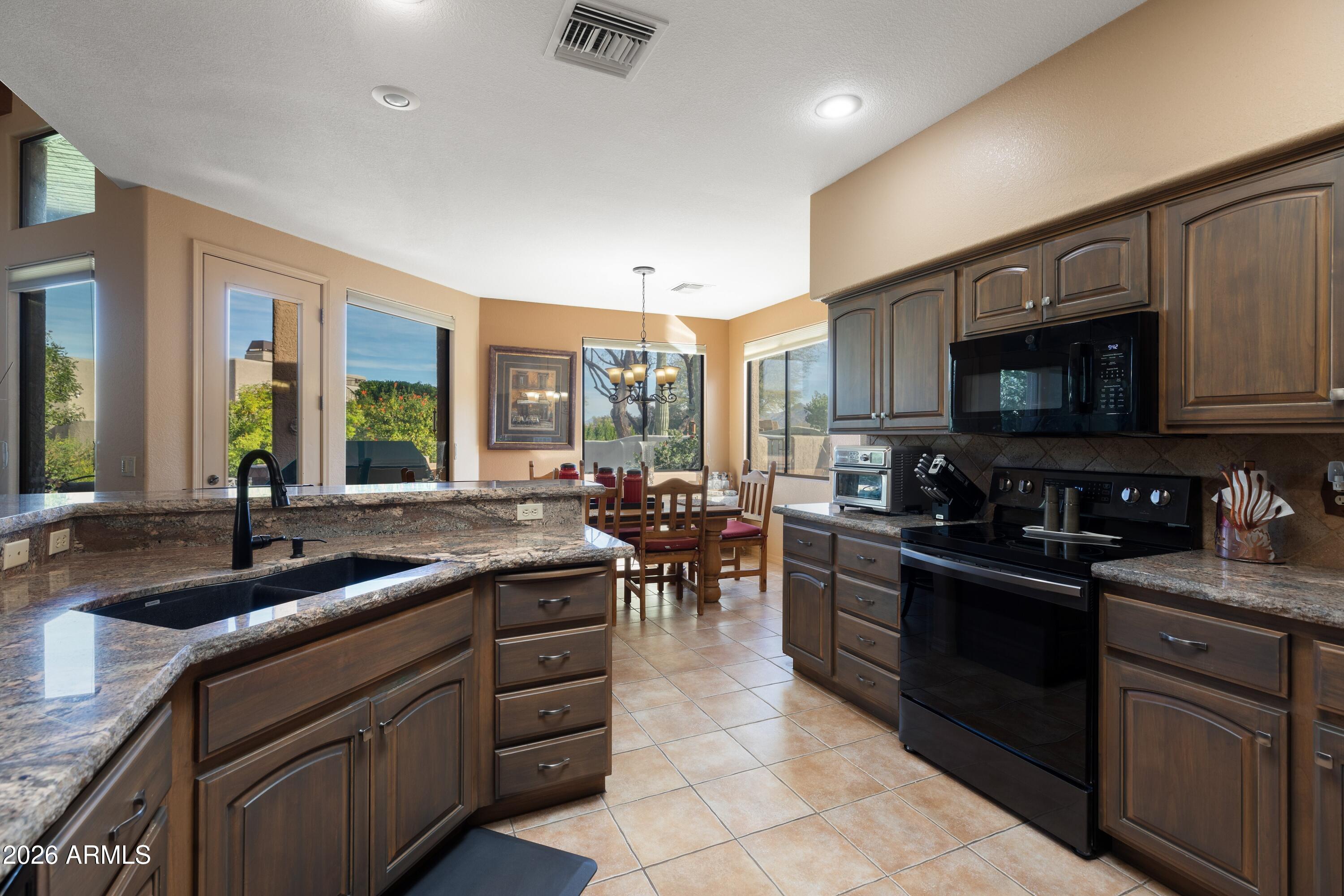 18622 North Tonto Verde Drive Rio Verde, AZ 85263 - Photo 4 of 47 a kitchen with stainless steel appliances granite countertop sink stove top oven and cabinets