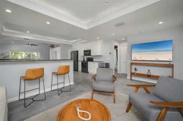 a living room with furniture kitchen view and a wooden floor