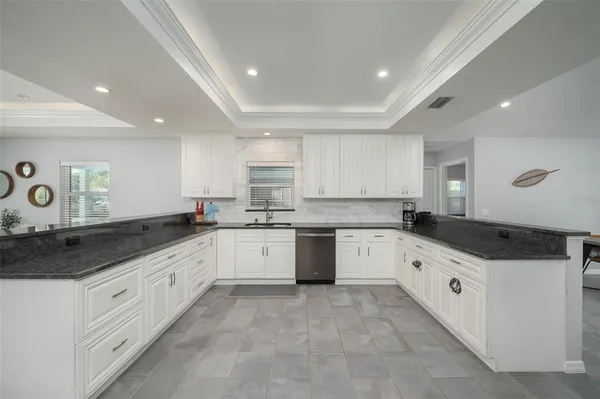 a kitchen with granite countertop a white stove top oven and white cabinets