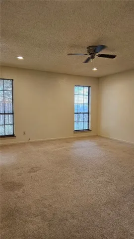 an empty room with windows and ceiling fan view