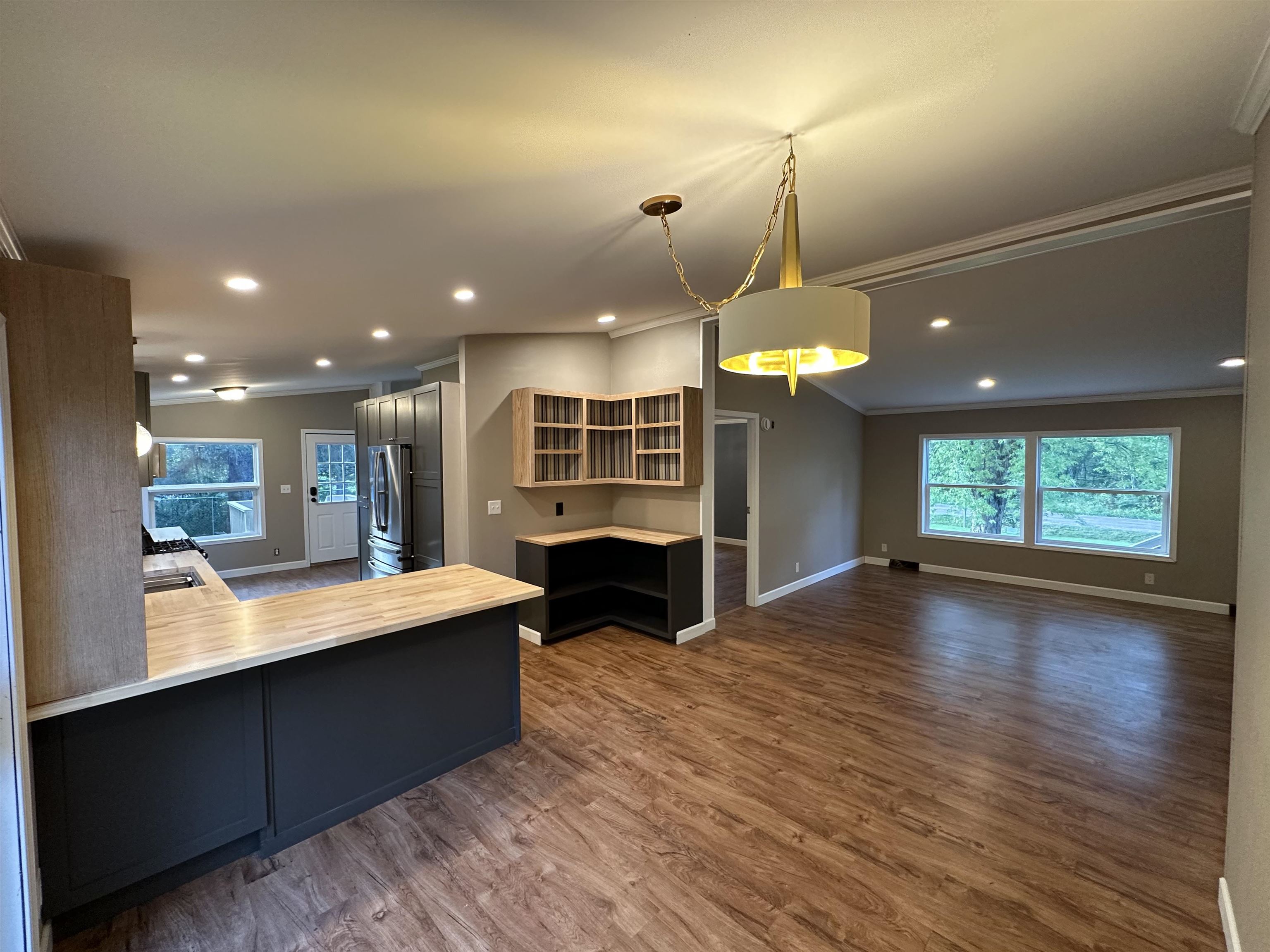 3748 Mulvahill Road Rice Lake, MN 55803 - Photo 10 of 26 open concept kitchen with crown molding, hanging light fixtures, dark wood-style floors, a peninsula, and healthy amount of natural light leading into the dinning area and living space.