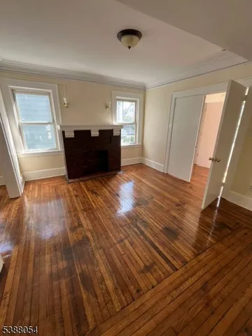 a view of an empty room with wooden floor and windows