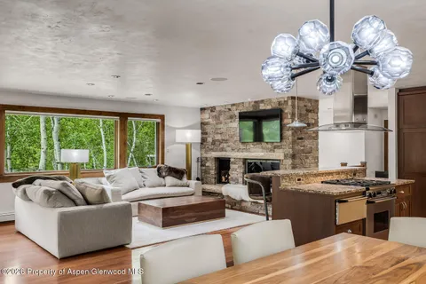a living room with fireplace furniture a chandelier and a large window