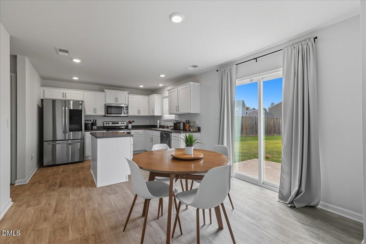 6854 Summerside Drive Whitsett, NC 27377 - Photo 15 of 49 a view of a dining room with furniture a kitchen and chandelier