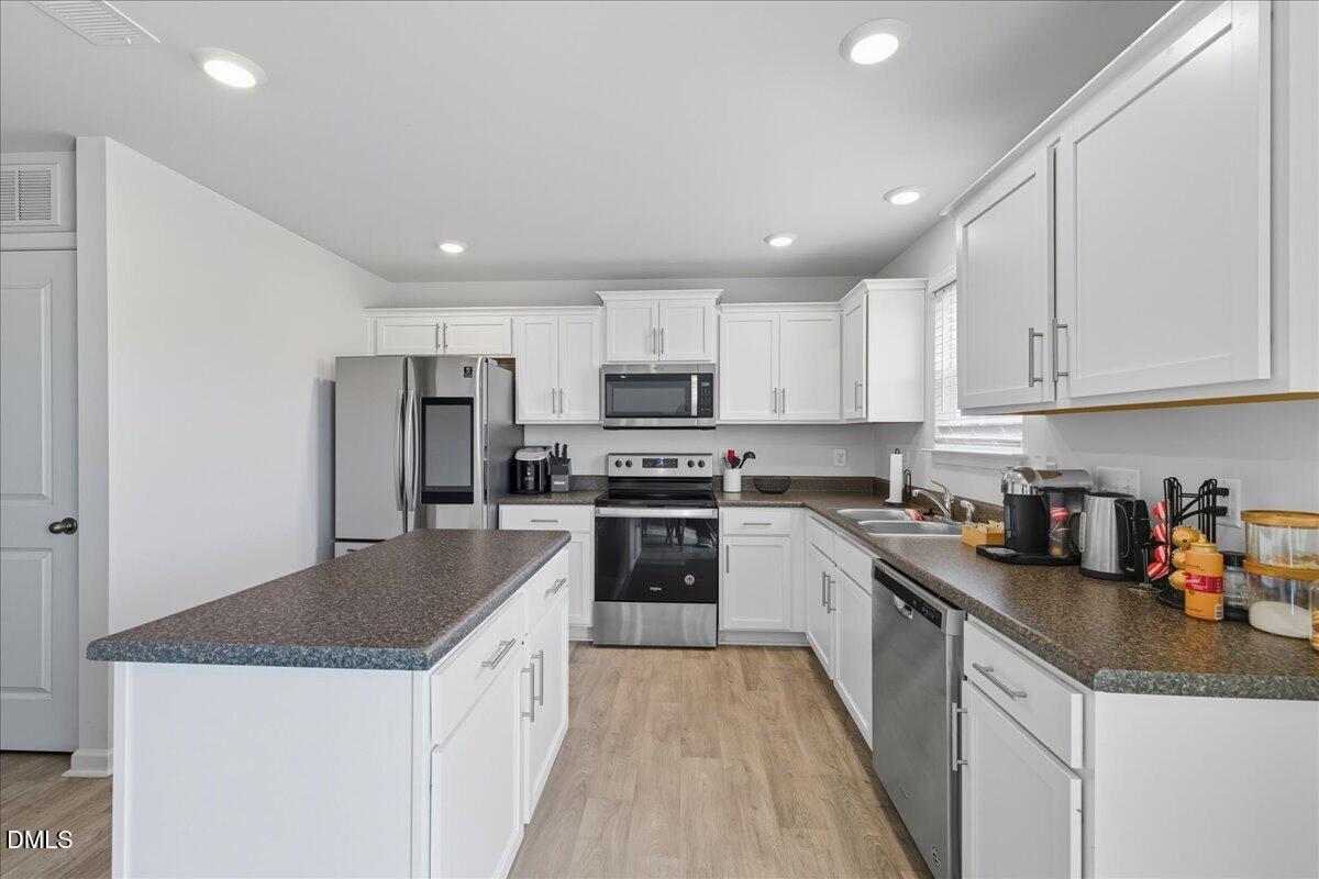 6854 Summerside Drive Whitsett, NC 27377 - Photo 17 of 49 a kitchen with stainless steel appliances granite countertop a refrigerator a sink dishwasher a stove and white countertops with wooden floor