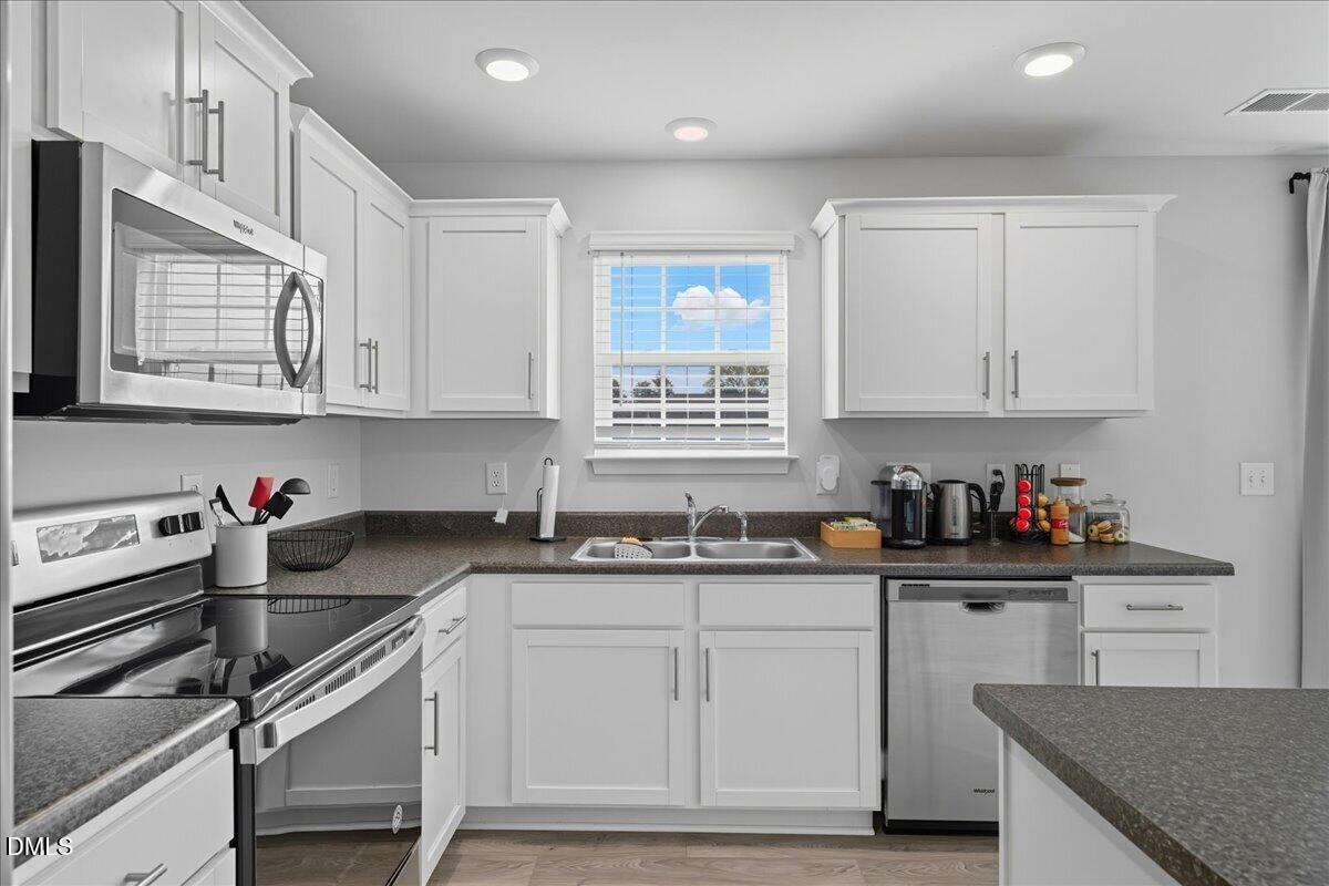 6854 Summerside Drive Whitsett, NC 27377 - Photo 19 of 49 a kitchen with stainless steel appliances granite countertop a sink stove and cabinets