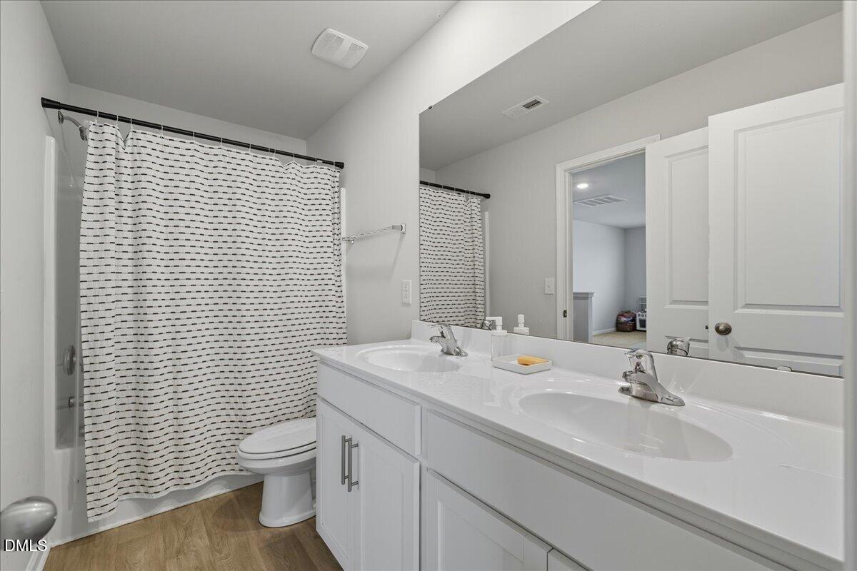 6854 Summerside Drive Whitsett, NC 27377 - Photo 33 of 49 a bathroom with a sink a toilet and mirror