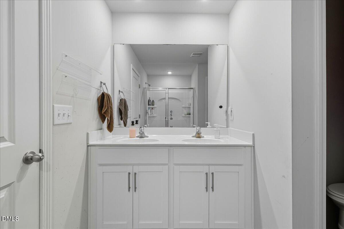 6854 Summerside Drive Whitsett, NC 27377 - Photo 37 of 49 a bathroom with a double vanity sink and mirror