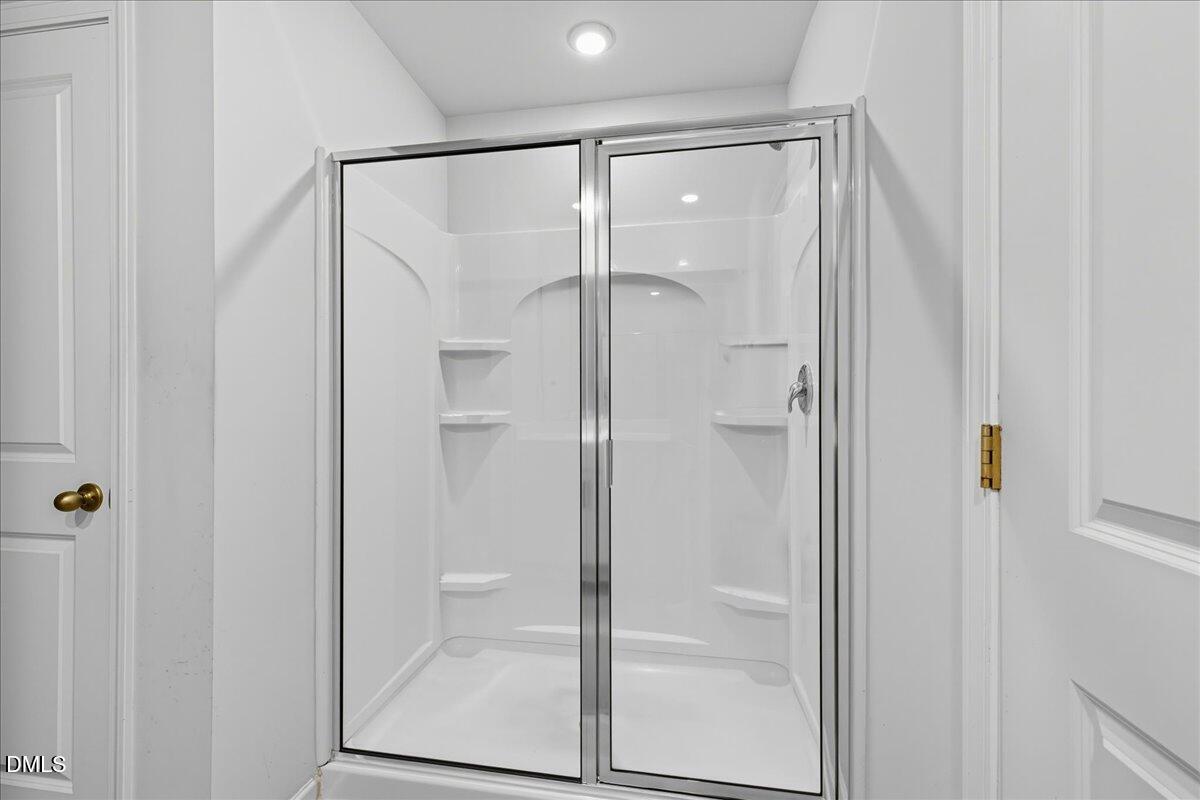 6854 Summerside Drive Whitsett, NC 27377 - Photo 38 of 49 a bathroom with a glass shower door