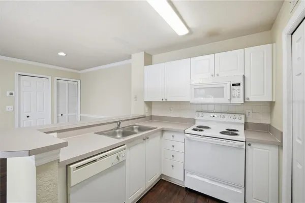 a kitchen with a sink a stove a refrigerator and white cabinets
