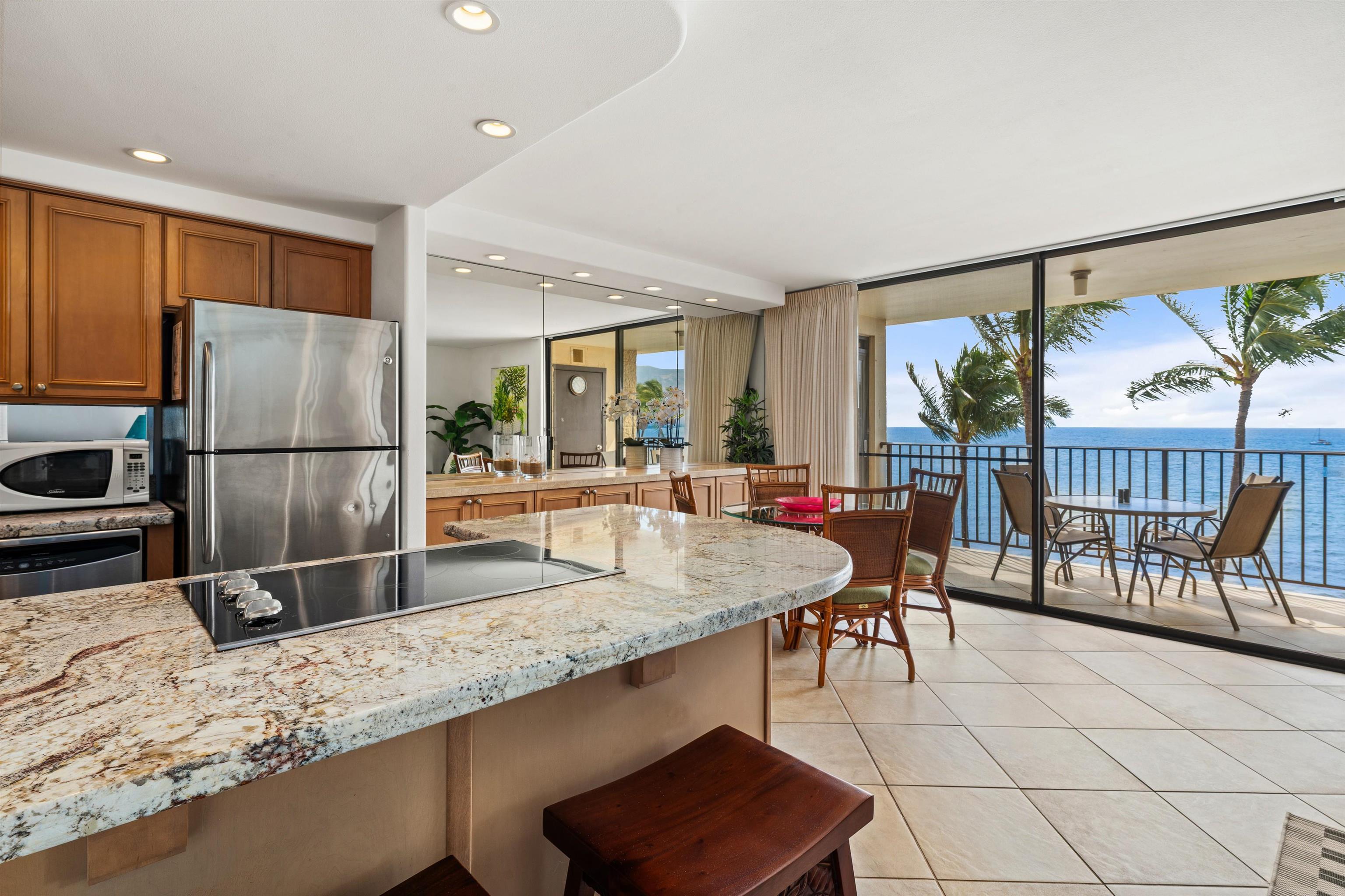 36 South Kihei Road, Unit 603 Kihei, HI 96753 - Photo 2 of 37 a kitchen with granite countertop a refrigerator a stove and white cabinets with wooden floor
