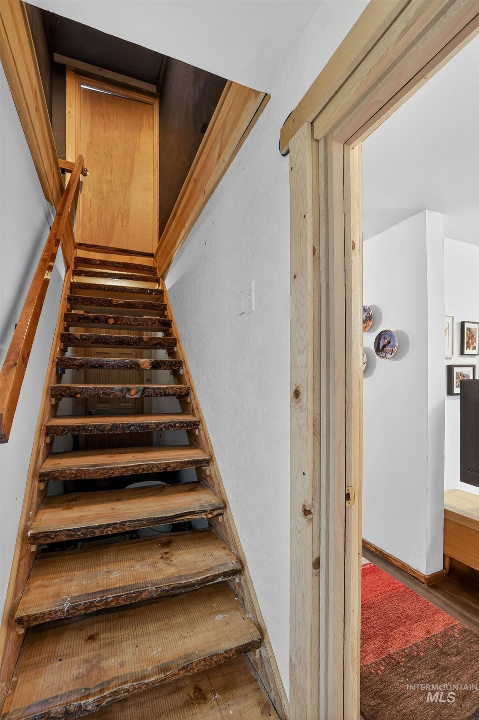 321 Secesh River Road McCall, ID 83638 - Photo 12 of 50 Natural wood staircase with bark-edge treads and a matching wood-paneled door