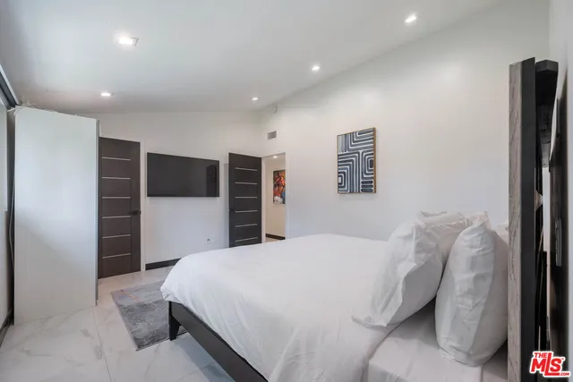 a spacious bedroom with a bed and a television