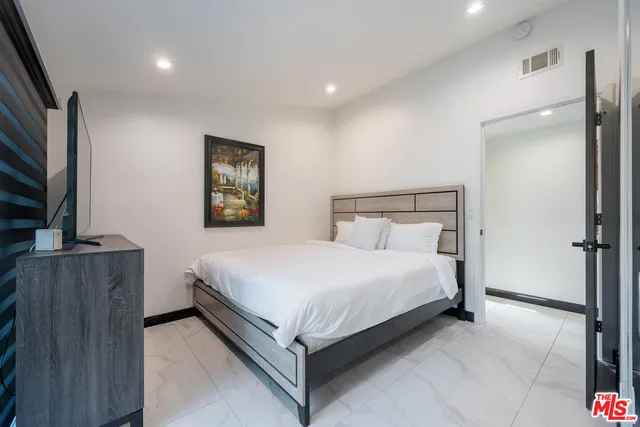 a bedroom with a bed and a flat tv screen on a dresser