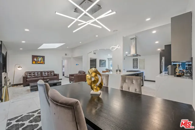 a living room with stainless steel appliances kitchen island granite countertop furniture a rug kitchen view and a chandelier