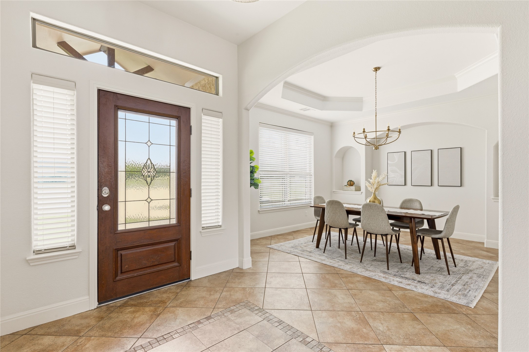 1432 Tom Sawyer Road Austin, TX 78737 - Photo 7 of 33 A spacious foyer with tile flooring transitions into an elegant dining area featuring tray ceilings and arched doorways.