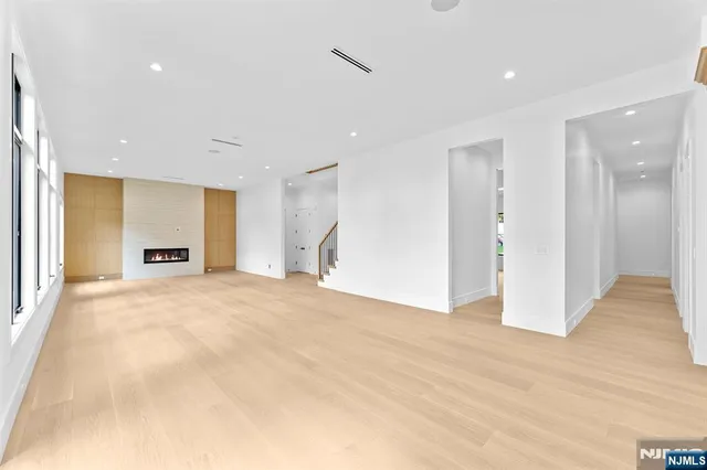 a view of an empty room with kitchen and window