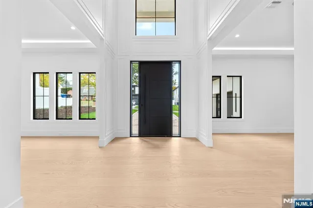 a view of an empty room with window and kitchen view