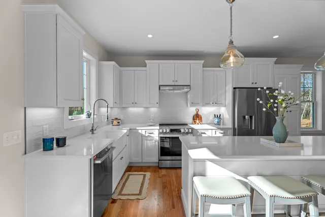 a kitchen with stainless steel appliances granite countertop a stove a sink a refrigerator a stove a dining table and chairs with wooden floor